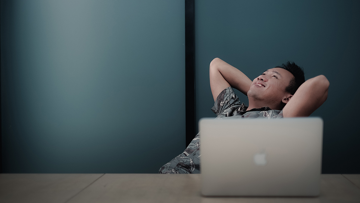 Man leaning back in chair in front of laptop