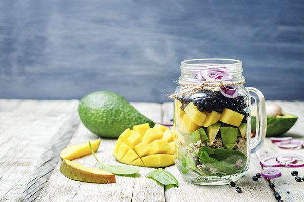 homemade healthy salads with black beans, vegetables, fruits, and quinoa in jar. toning. selective Focus