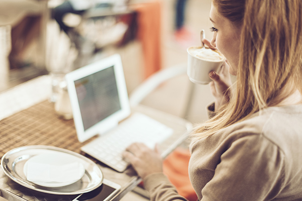 Woman online shopping with a laptop and cup of coffee