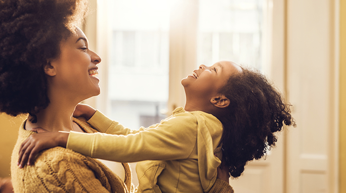 Young happy African American mother playing with her little girl at home