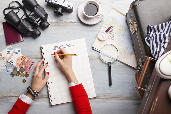 Woman writing out travel plans with map