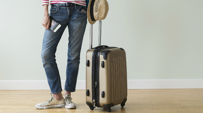 Woman with rolling suitcase and passport