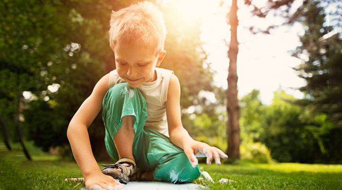 Little boy touching stepping stones in back yard