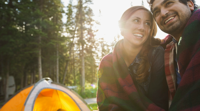 Young couple wrapped in blanket camping