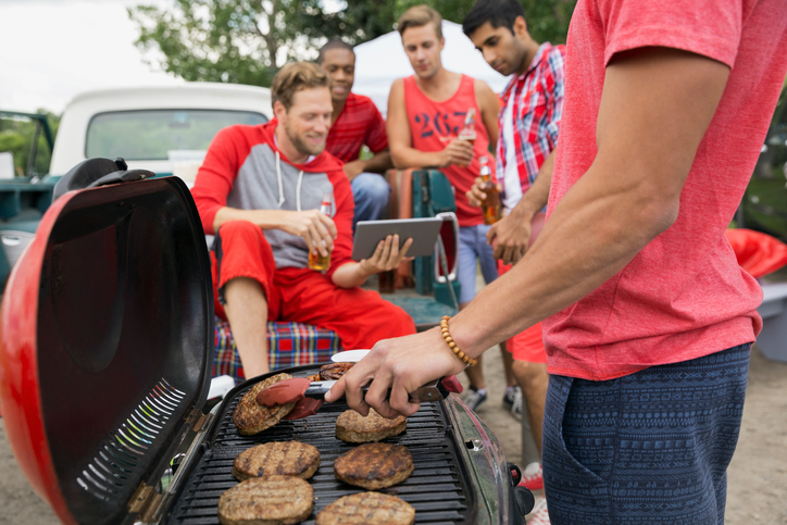 Man grilling at tailgate barbecue in field
