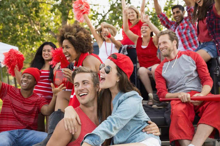 Friends cheering at tailgate barbecue in field