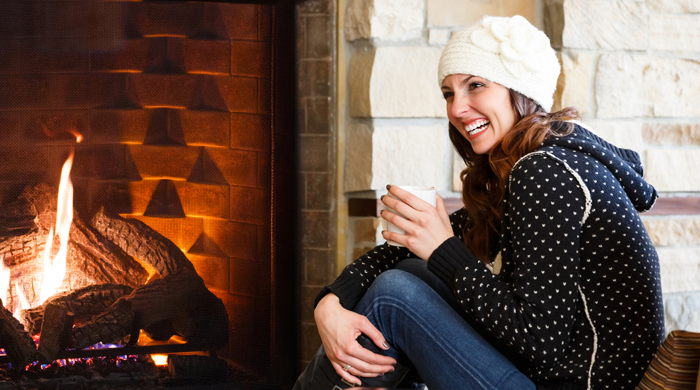 woman sitting by a fire in a fall sweater