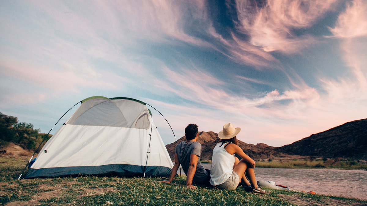 Man and woman sitting next to a tent