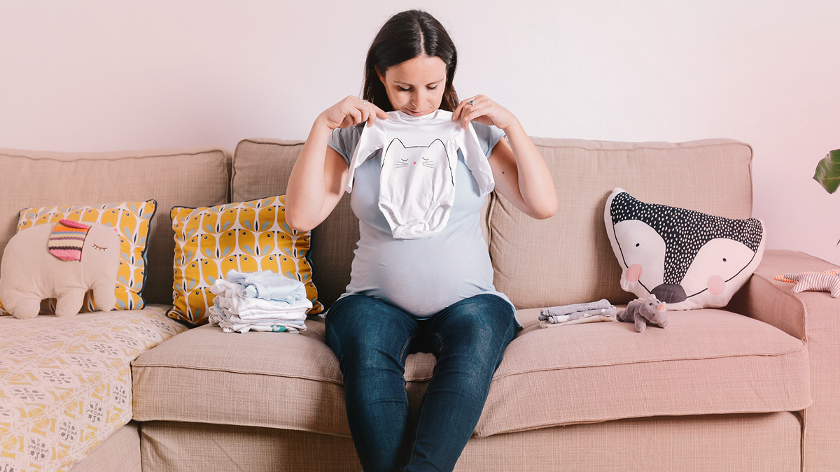 Pregnant woman holding a onesie