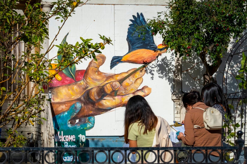 A mural on a building with students standing in front.