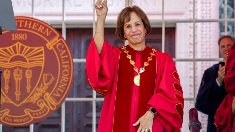 Carol Folt giving the peace sign at graduation.