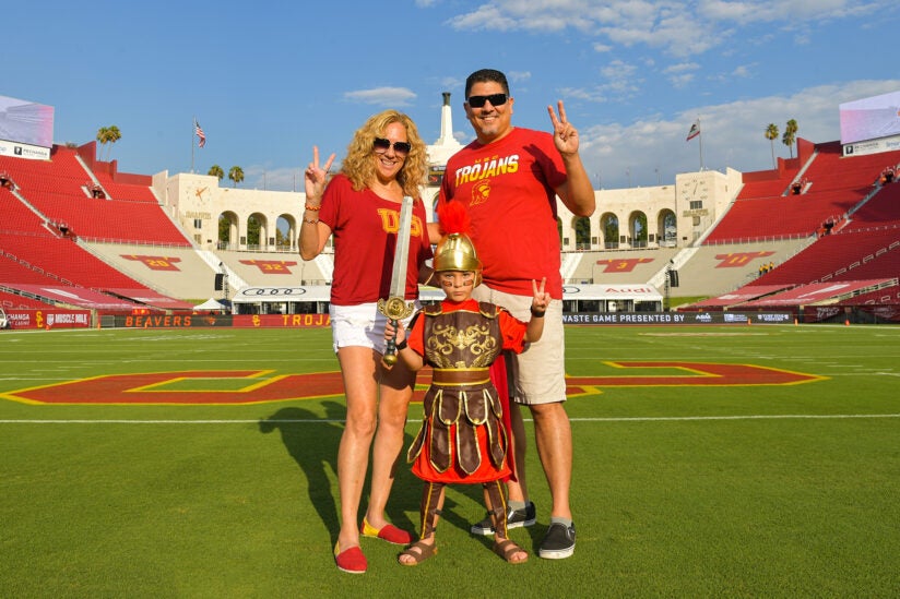 A family standing on the USC football team. Little boy is dressed up in a Trojan costume.